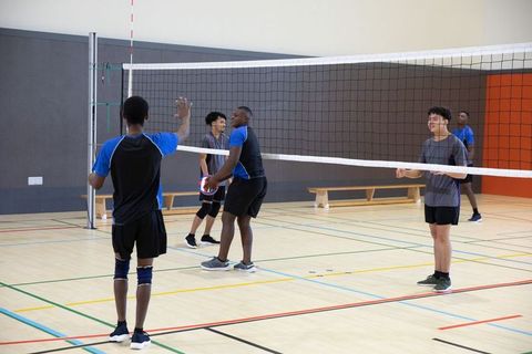 High school male teens playing indoor volleyball practicing teamwork, passing and serving