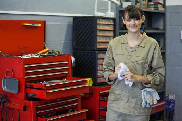 Portrait of female mechanic standing beside tool kit at a repair garage