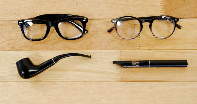 Eyeglasses and spectacles, traditional pipe and modern vape on wooden surface representing choice in lifestyle and preferences. Perfect for advertising eyewear, tobacco products, lifestyle magazines, blogs about modern vs vintage trends, or comparison visuals.