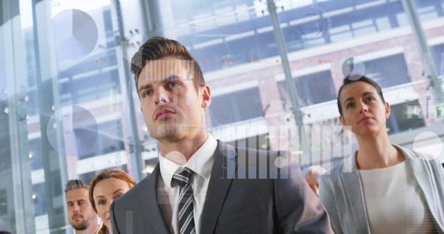 Business professionals analyzing digital charts in modern atrium