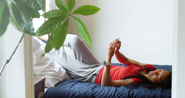 Woman using mobile phone in bedroom at home