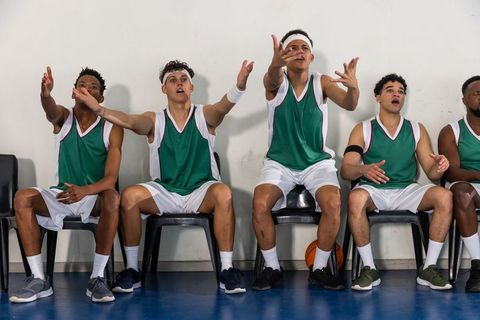 Excited male teammates cheering energetically on basketball court