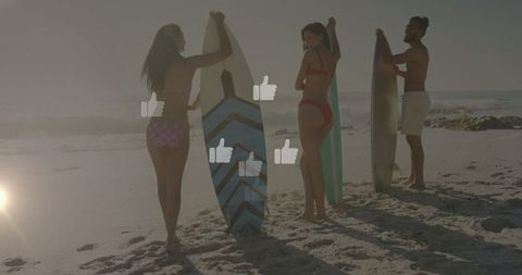 Surfers holding boards on beach at sunset with thumbs up icons overlay