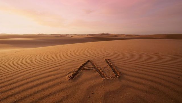 AI letters carved into rippled desert sand at dawn with pastel pink sky and vast dunes