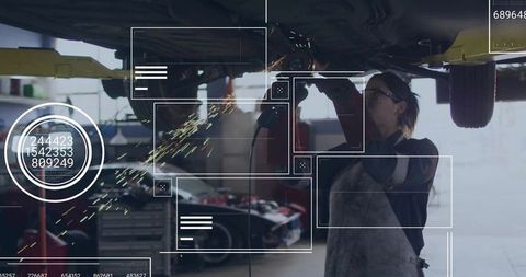 Female Mechanic Grinding Under Lifted Car Producing Sparks in Auto Repair Garage