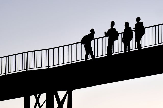 Silhouette of Four People Walking on Bridge at Sunset - Download Free Stock Images Pikwizard.com