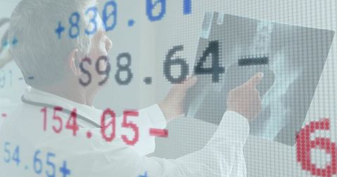 Senior doctor pointing at chest xray with digital medical data overlay for diagnostic imaging