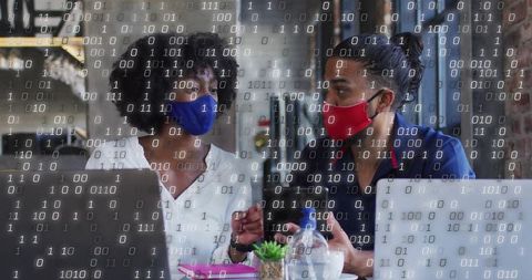 Colleagues Collaborating on Laptops Overlaid with Binary Code