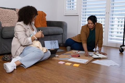 African american and asian women designers collaborating on moodboard with fabric swatches