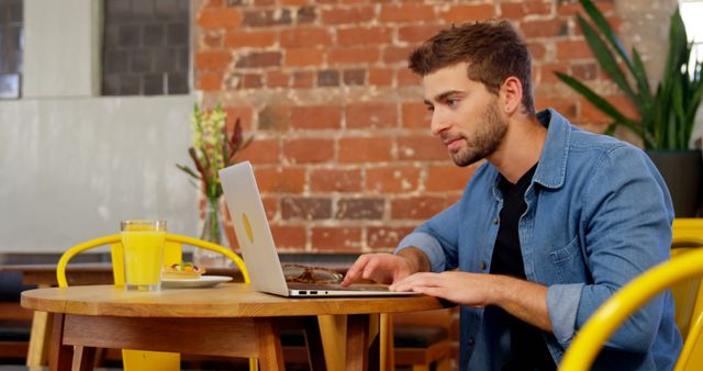 Young Man Working on Laptop at Cozy Cafe with Brick Wall Background - Download Free Stock Images Pikwizard.com