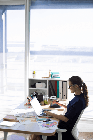 Businesswoman Working on Laptop at Desk in Bright Office with Transparent Window - Download Free Stock Videos Pikwizard.com