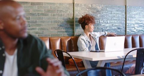 African american woman working on laptop in cafe with leather banquette and tiled wall