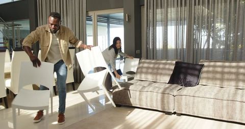 Two People in Modern Living Room Arranging Chairs
