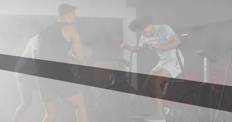 High-intensity air bike training with hazy studio lighting and diagonal graphic stripe