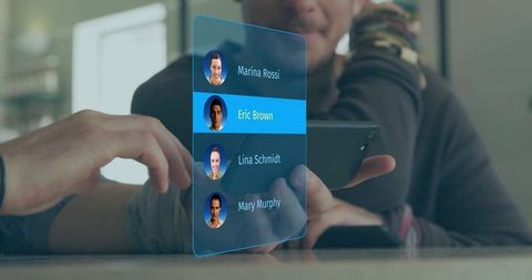 Man tapping holographic contact panel while holding smartphone at lounge table