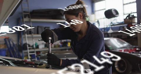 Female mechanic tightening engine bolts with breaker bar in daylight garage workshop