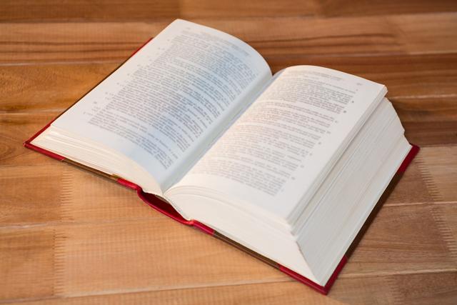 Open book with visible text on a wooden table. Ideal for educational content, literature blogs, study guides, and academic presentations. Can be used to represent knowledge, learning, and research.