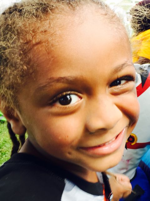 This close-up of a smiling child with braided hair radiates positivity and joy. Ideal for campaigns focused on childhood, happiness, parental love, or outdoor activities. Use in educational or childcare apps, parenting blogs, or advertising promoting family and kids' products.