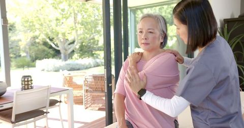 Physical Therapist Assisting Senior Asian Woman with Shoulder Exercise