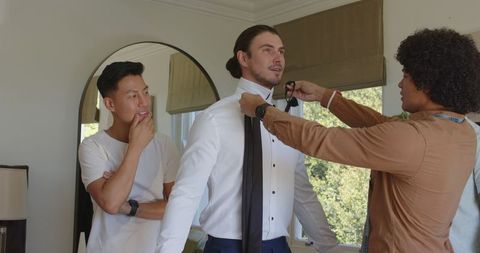 Groom preparing for wedding with friends in dressing room