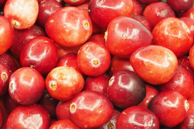 Close-up view of a bunch of fresh ripe cranberries. Ideal for use in health and wellness articles, recipes, and food-related marketing materials. This vibrant and detailed image highlights the natural texture and color of the cranberries, promoting organic and healthy eating.