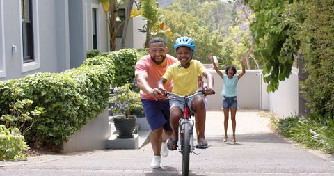 Father Teaching Son to Ride Bicycle with Family Cheering in Suburban Neighborhood - Download Free Stock Images Pikwizard.com