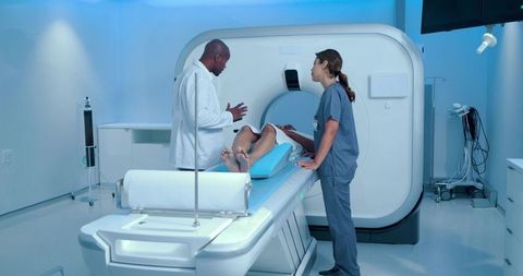 Medical team positioning patient for ct scan in modern radiology suite with blue lighting