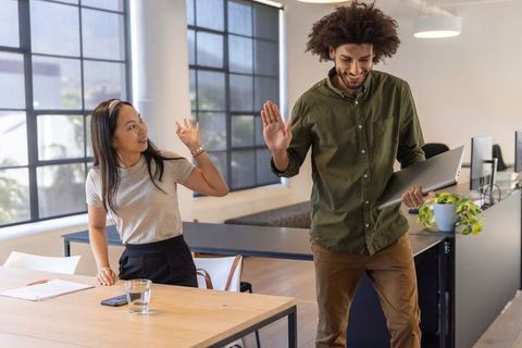 Diverse Coworkers High-Fiving in Open Office Workspace