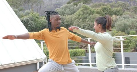 Rooftop Partner Yoga Practicing Warrior Pose for Urban Fitness and Wellness Routine
