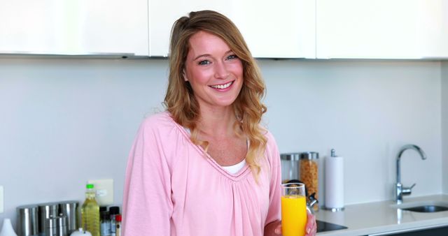 Smiling Woman Holding Glass of Orange Juice in Modern Kitchen - Download Free Stock Images Pikwizard.com