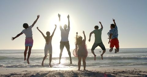Group of Friends Jumping on Beach with Sunlit Silhouettes - Download Free Stock Images Pikwizard.com