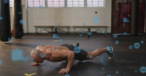 Muscular athlete performing pushup with digital icons overlay in industrial gym space