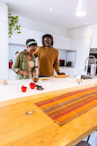 African american couple cooking together at modern kitchen island smiling and relaxed