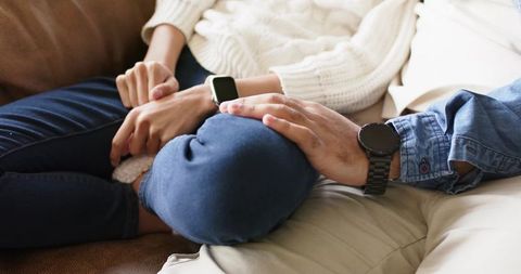 Couple sharing quiet moment on couch showing smartwatch and wristwatch closeup