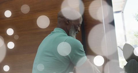 Mature man relaxing in modern entryway with mint-green polo, wood wall and glass door