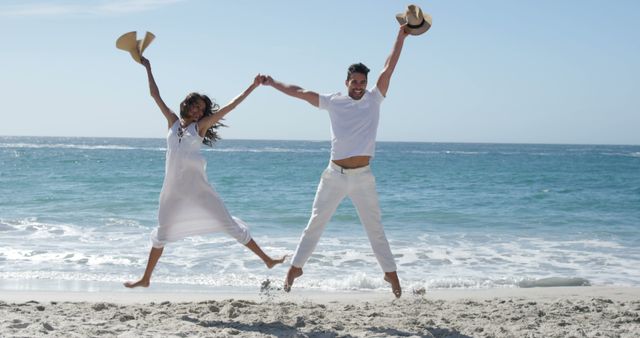 Happy couple jumping together at the beach