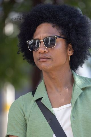 Urban man standing wearing sunglasses and green shirt, afro, nose ring, casual portrait