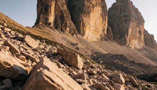 Sunlit limestone towers towering over rocky alpine talus during golden hour