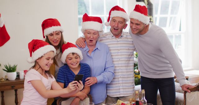 Family Celebrating Christmas Together with Santa Hats and Smartphone - Download Free Stock Images Pikwizard.com