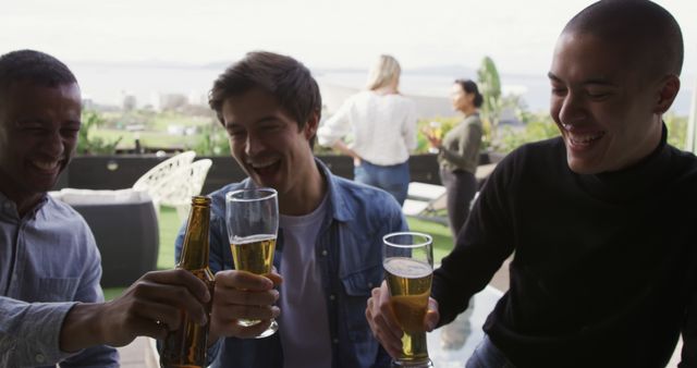 Diverse male colleagues drinking toast on sunny rooftop. Lifestyle, friendship, togetherness and free time, unaltered.