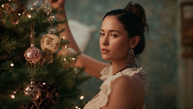 Elegant Woman Decorating Christmas Tree with Baubles at Home