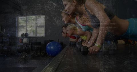 Five adults holding plank on dumbbells during group strength training session