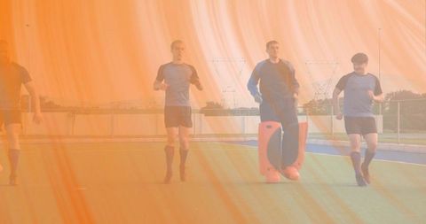 Team jogging on artificial turf during field hockey goalkeeper training drill