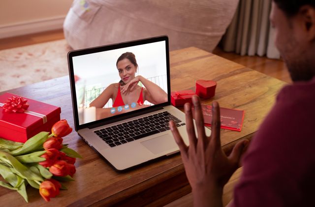 Beautiful caucasian young woman talking with biracial boyfriend waving hand during online dating. unaltered, online dating, video call and distant valentine day celebration.