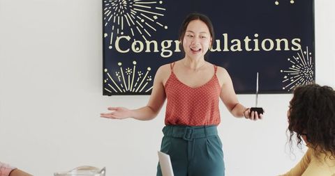 Happy team members celebrating with congratulations sign in office