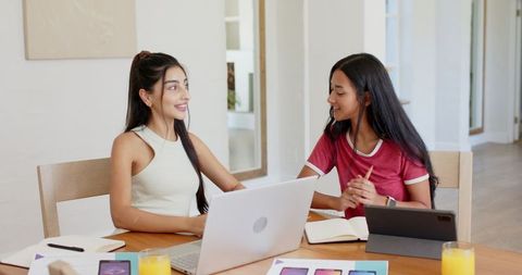 Diverse Friends Collaborating at Home Table with Laptop and Notes
