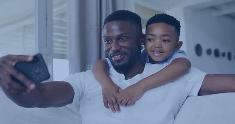 Happy African American Father and Son Taking Selfie on Couch
