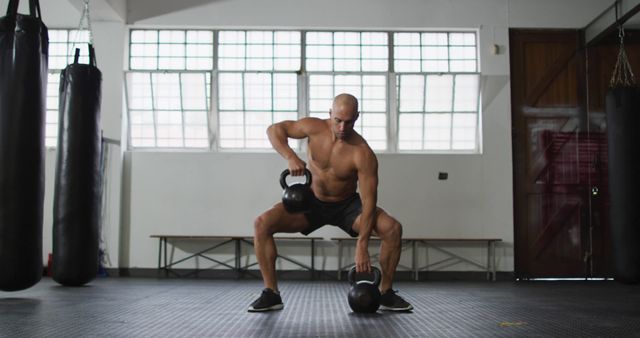 Muscular man squatting, lifting kettlebells in gym. Ideal for fitness blog, gym promotions, workout guides, articles on strength training, exercise routine illustrations.