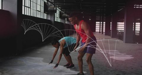 Athletic partners performing dynamic squat and mobility drill in industrial warehouse