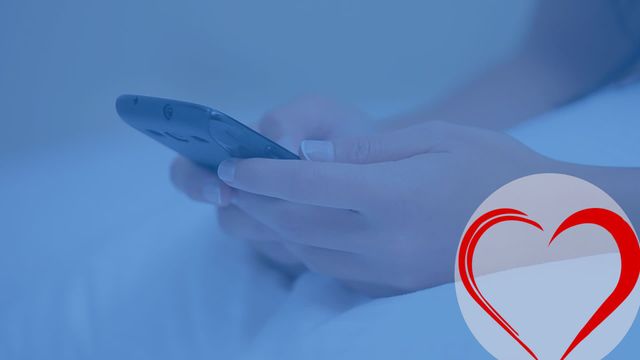 Hands are holding a smartphone, engaging in digital communication as a prominent heart-shaped icon appears. The blue tone suggests a technological and modern theme, alluding to digital connectivity or relationships. Suitable for illustrating modern communication, online technology themes, or graphics/content about digital love and connectivity.